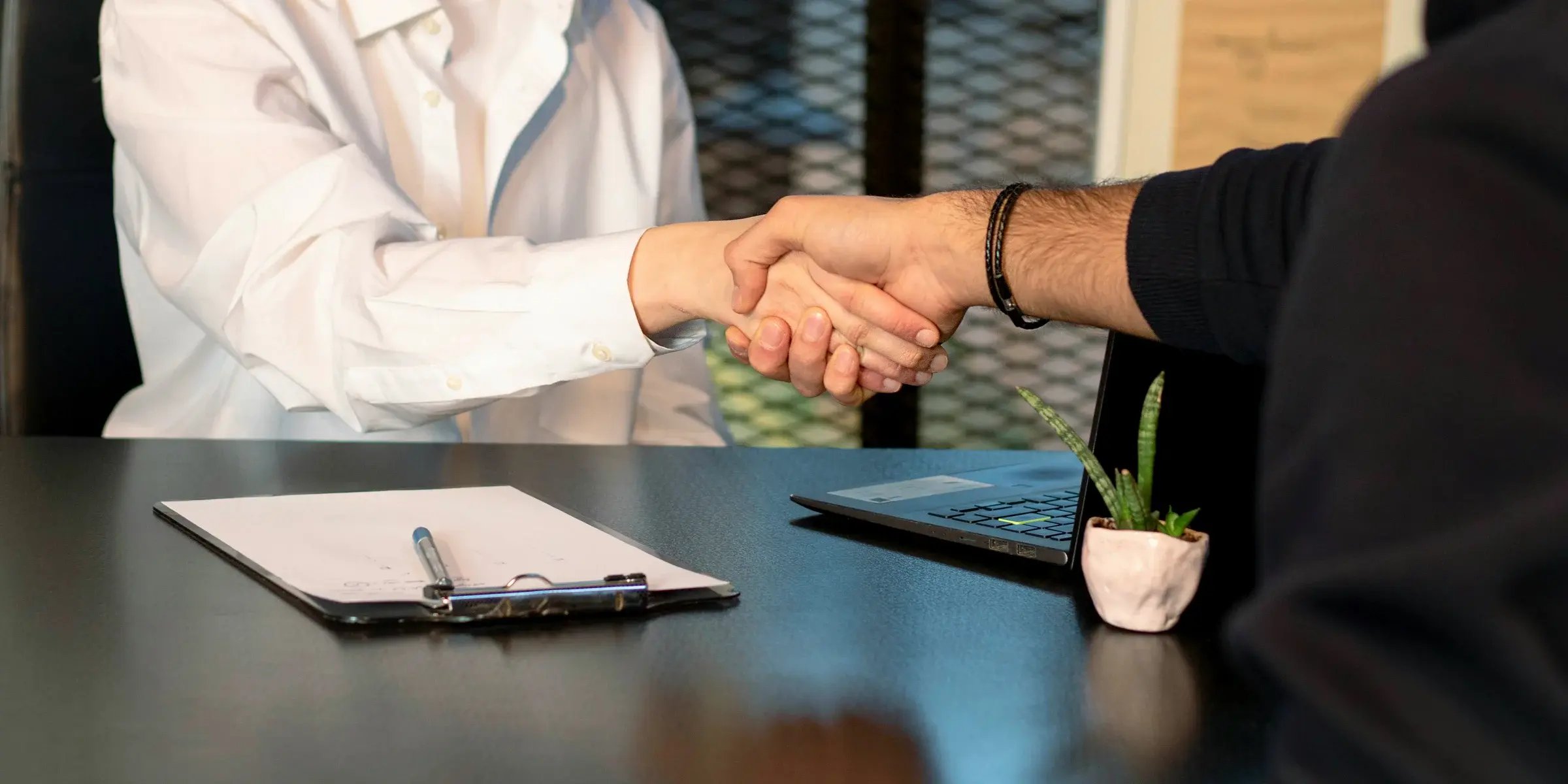 Two people shaking hands across a desk